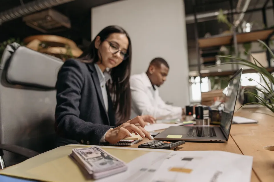 Two accountants working with a laptop and calculator in an office