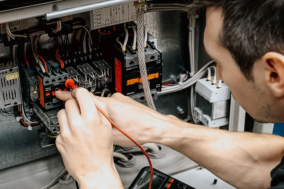 An electrician testing connections in an open electrical panel