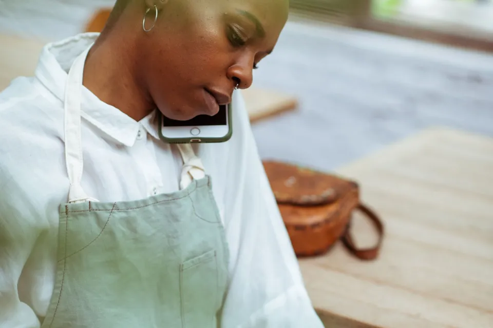 A café worker on a phone call while checking orders at a table